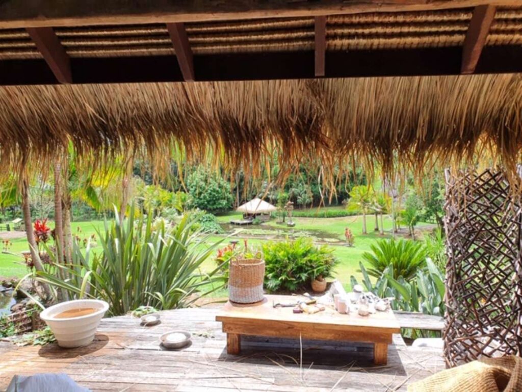 Looking out at a garden from under a Bali thatched roof hut
