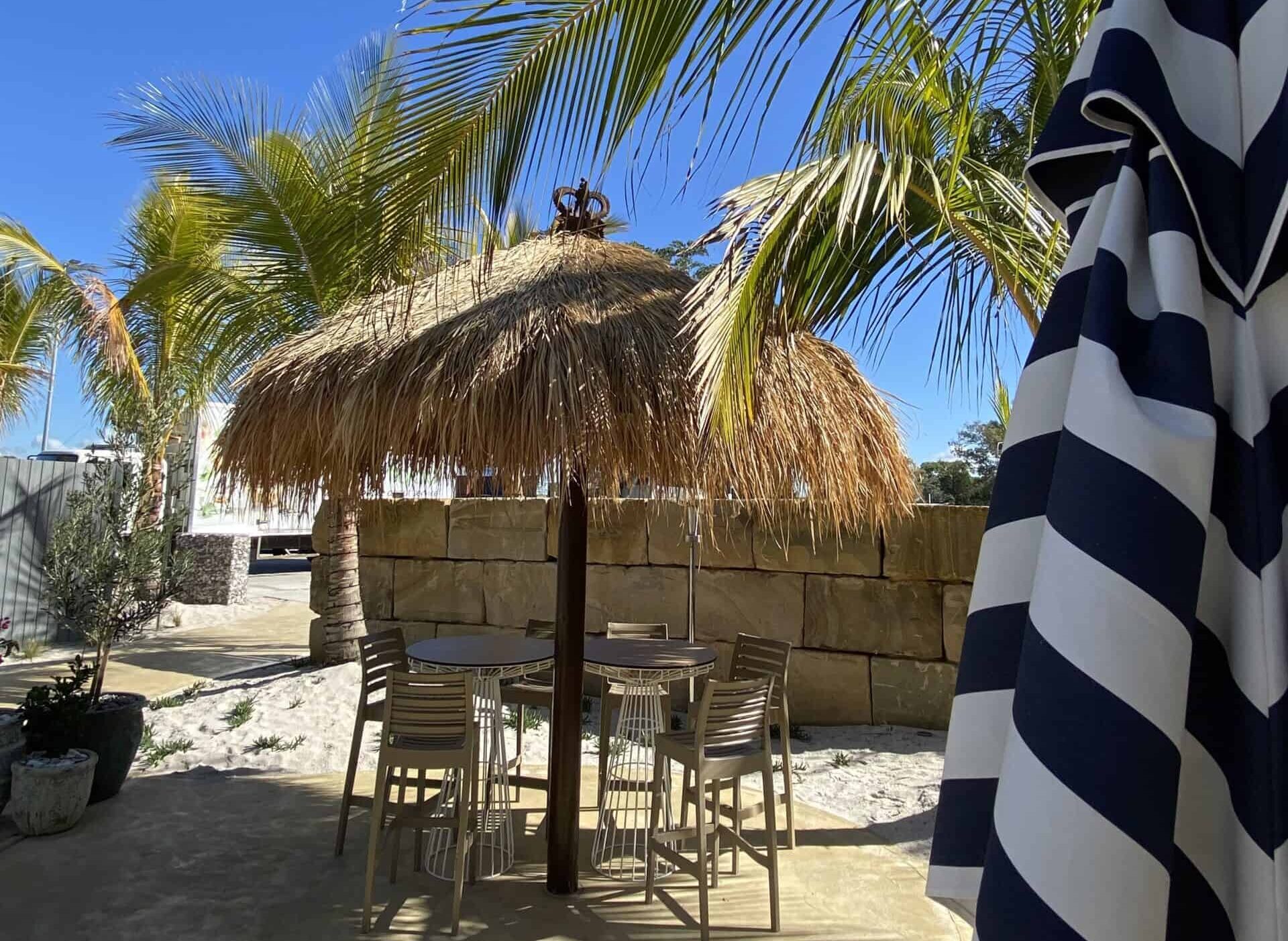 A quality thatched umbrella providing shade to an outdoor dining area on the Sunshine coast.