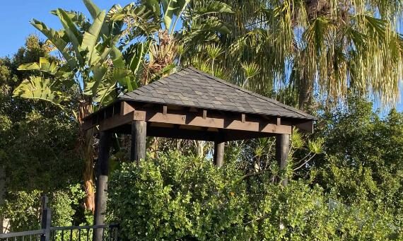 A shingle roof gazebo on the Sunshine Coast surrounded by greenery.